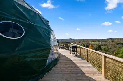 a green train sitting on a wooden deck at 'The Bear Dome' with Barrel Hot Tub in Franklin in Franklin
