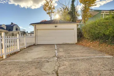 a garage with a white fence and a driveway at Easy Commute to Newark and NYC! Extended Stay Unit in Irvington