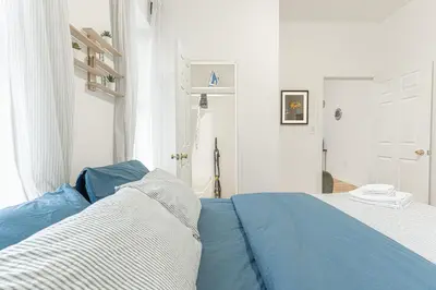 a white bedroom with a blue bed and a door at Modern Comfort 2BR with Washer & Dryer Near Subway & LGA in Corona