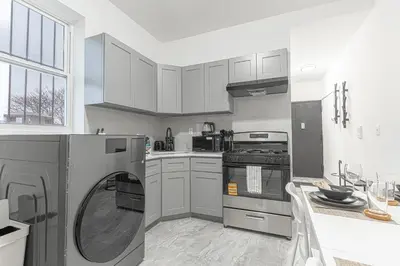 a kitchen with a washing machine in the middle at Modern Comfort 2BR with Washer & Dryer Near Subway & LGA in Corona