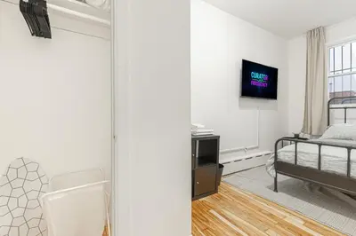 a bedroom with a bed and a tv on a wall at Modern Comfort 2BR with Washer & Dryer Near Subway & LGA in Corona