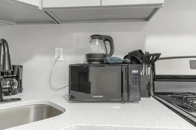 a microwave sitting on top of a kitchen counter at Modern Comfort 2BR with Washer & Dryer Near Subway & LGA in Corona