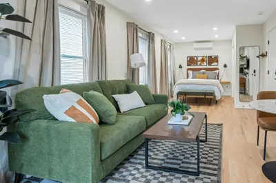 a living room with a green couch and a bed at Glenbrook Suites in Stamford