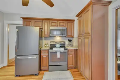 a kitchen with wooden cabinets and a refrigerator at The Game House Arcade West Hartford in West Hartford