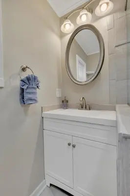 a white bathroom with a sink and a mirror at The Game House Arcade West Hartford in West Hartford
