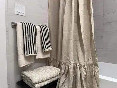 a bathroom with a shower with towels and a tub at Lux Bronx Apt Rooftop, Pool, Gym, Cinema in Mott Haven