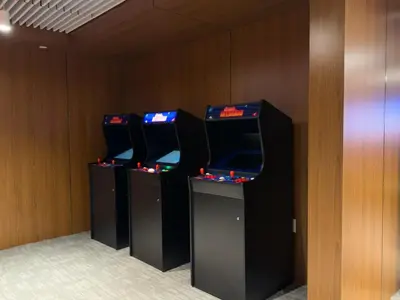 three video game machines lined up in a room at Lux Bronx Apt Rooftop, Pool, Gym, Cinema in Mott Haven