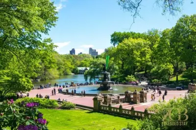 people walking around a fountain in a park at Spacious 1-Bedroom Retreat Near Central Park in New York