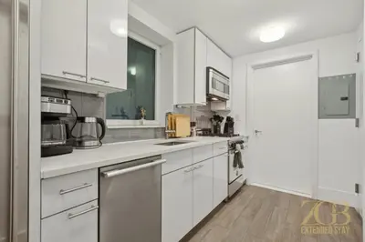 a white kitchen with white cabinets and appliances at Spacious 1-Bedroom Retreat Near Central Park in New York