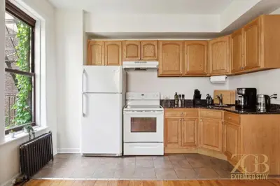 a kitchen with wooden cabinets and a white refrigerator at Gorgeous 2 Bedroom Apt in UES in New York