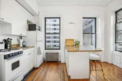 a kitchen with white cabinets and a wooden floor at Beautiful 1-Bedroom in the Upper East Side in New York