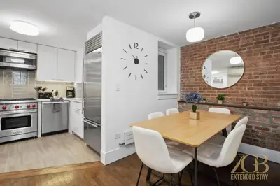 a kitchen with a wooden table and a brick wall at Gorgeous 2-Bedroom Retreat in the Upper East Side in New York