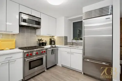 a kitchen with white cabinets and a stainless steel refrigerator at Gorgeous 2-Bedroom Retreat in the Upper East Side in New York
