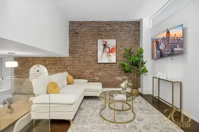 a living room with a white couch and a brick wall at Gorgeous 2-Bedroom Retreat in the Upper East Side in New York