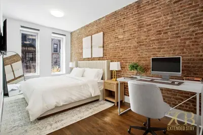 a bedroom with a brick wall and a desk with a computer at Gorgeous 2-Bedroom Retreat in the Upper East Side in New York