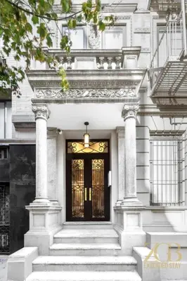 a white house with a black door and stairs at Gorgeous 2-Bedroom Retreat in the Upper East Side in New York