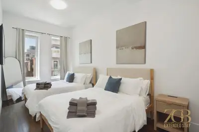 two beds in a bedroom with white walls and windows at Fully Furnished PH Duplex with Private Outdoor Space in New York