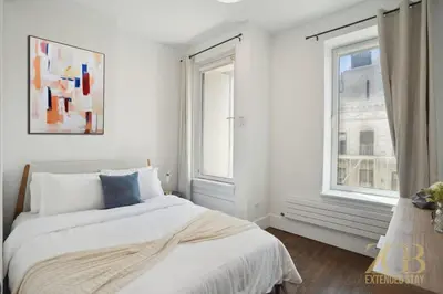 a white bedroom with a bed and two windows at Fully Furnished PH Duplex with Private Outdoor Space in New York