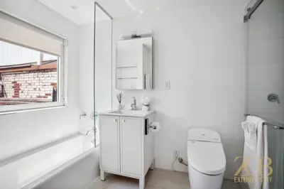 a white bathroom with a toilet and a sink at Fully Furnished PH Duplex with Private Outdoor Space in New York