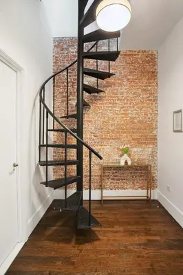 a black spiral staircase in front of a brick wall at Fully Furnished PH Duplex with Private Outdoor Space in New York