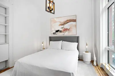 a white bedroom with a white bed and windows at Classic NYC Brownstone 2Br Apartment in Prime Chelsea in New York