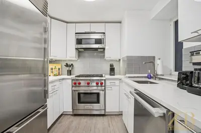 a kitchen with white cabinets and a stainless steel oven at Charming UES 1BR Duplex Near Central Park in New York