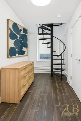 a living room with a staircase and a wooden cabinet at Charming UES 1BR Duplex Near Central Park in New York