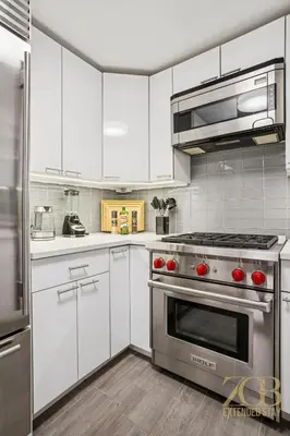 a kitchen with white cabinets and a stainless steel oven at Charming UES 1BR Duplex Near Central Park in New York