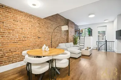 a living room with a brick wall and a table and chairs at Charming UES 1BR Duplex Near Central Park in New York