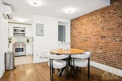 a kitchen with a wooden table and a brick wall at Charming UES 1BR Duplex Near Central Park in New York
