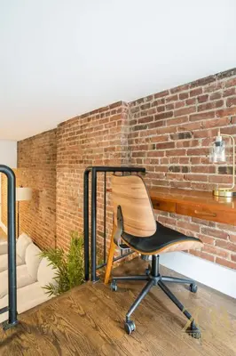 a black chair sitting in front of a brick wall at Charming UES 1BR Duplex Near Central Park in New York
