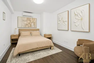 a white bedroom with a bed and a chair at Charming UES 1BR Duplex Near Central Park in New York
