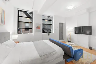 a white bedroom with a large bed and a tv at Beautifully Renovated Studio in Prime Manhattan in New York