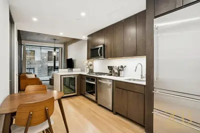 a kitchen with wooden cabinets and a table and a sink at Modern 2BR Terrace WD & Elevator in NoMad in New York