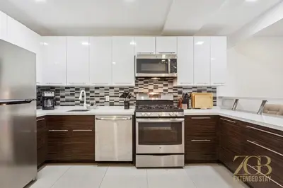 a kitchen with wooden cabinets and stainless steel appliances at Stylish 2-Bedroom Near Central Park - Laundry - Elevator in New York