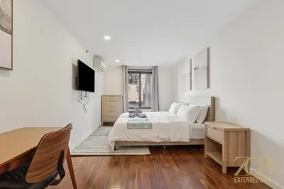 a white bedroom with a bed and a television at Stylish 2-Bedroom Near Central Park - Laundry - Elevator in New York
