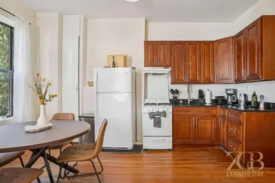 a kitchen with a white refrigerator and a table at Stylish 2-Bedroom Apartment in the Upper East Side in New York