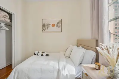 a white bedroom with a white bed and a window at Stylish 2-Bedroom Apartment in the Upper East Side in New York