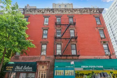 a red brick building on a city street at Stylish 2-Bedroom Apartment in the Upper East Side in New York