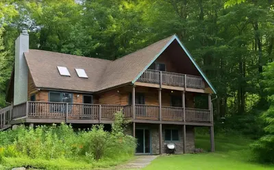 a large wooden house with a large deck at Log Cabin And Cottages At Equestrian House in Pleasant Mount
