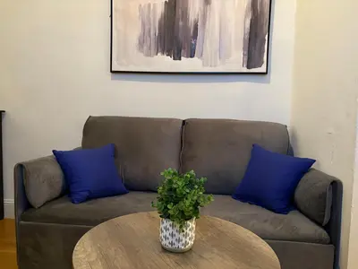 a couch with two blue pillows and a table at Signature by Times Square in New York
