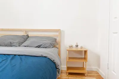 a bedroom with a bed and a wooden night stand at Comfy 2B Near LGA & Subway with Washer & Dryer in Corona