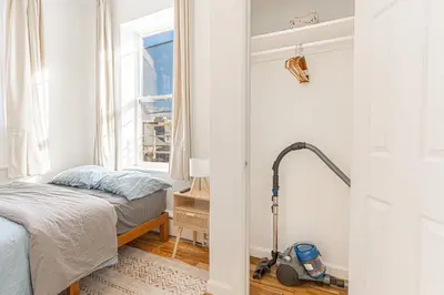 a bedroom with a bed and a vacuum in a room at Comfy 2B Near LGA & Subway with Washer & Dryer in Corona