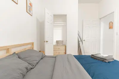 a white bedroom with a bed with blue sheets at Comfy 2B Near LGA & Subway with Washer & Dryer in Corona