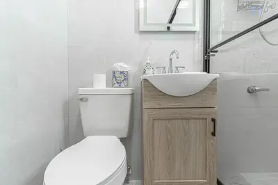 a white bathroom with a toilet and a sink at Comfy 2B Near LGA & Subway with Washer & Dryer in Corona
