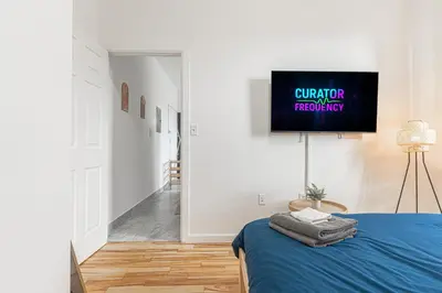 a bedroom with a bed and a tv on a wall at Comfy 2B Near LGA & Subway with Washer & Dryer in Corona
