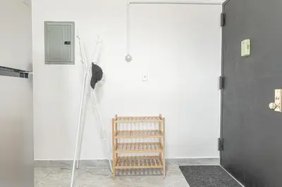 a room with a white wall and a wooden chair at Comfy 2B Near LGA & Subway with Washer & Dryer in Corona