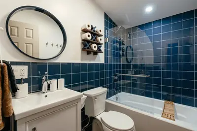 a blue tiled bathroom with a toilet and a sink at Mural Art Cabin With Pond And Hot Tub in Narrowsburg