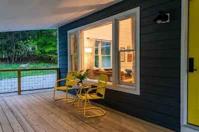 a screened in porch with a table and chairs on a deck at Hare & Hollow with Hot Tub & Fenced Yard