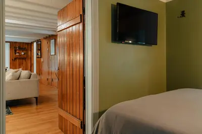 a bedroom with a bed and a flat screen tv at Creekfront Cabin Sauna & Hot Tub Hikers Hollow in Cuddebackville